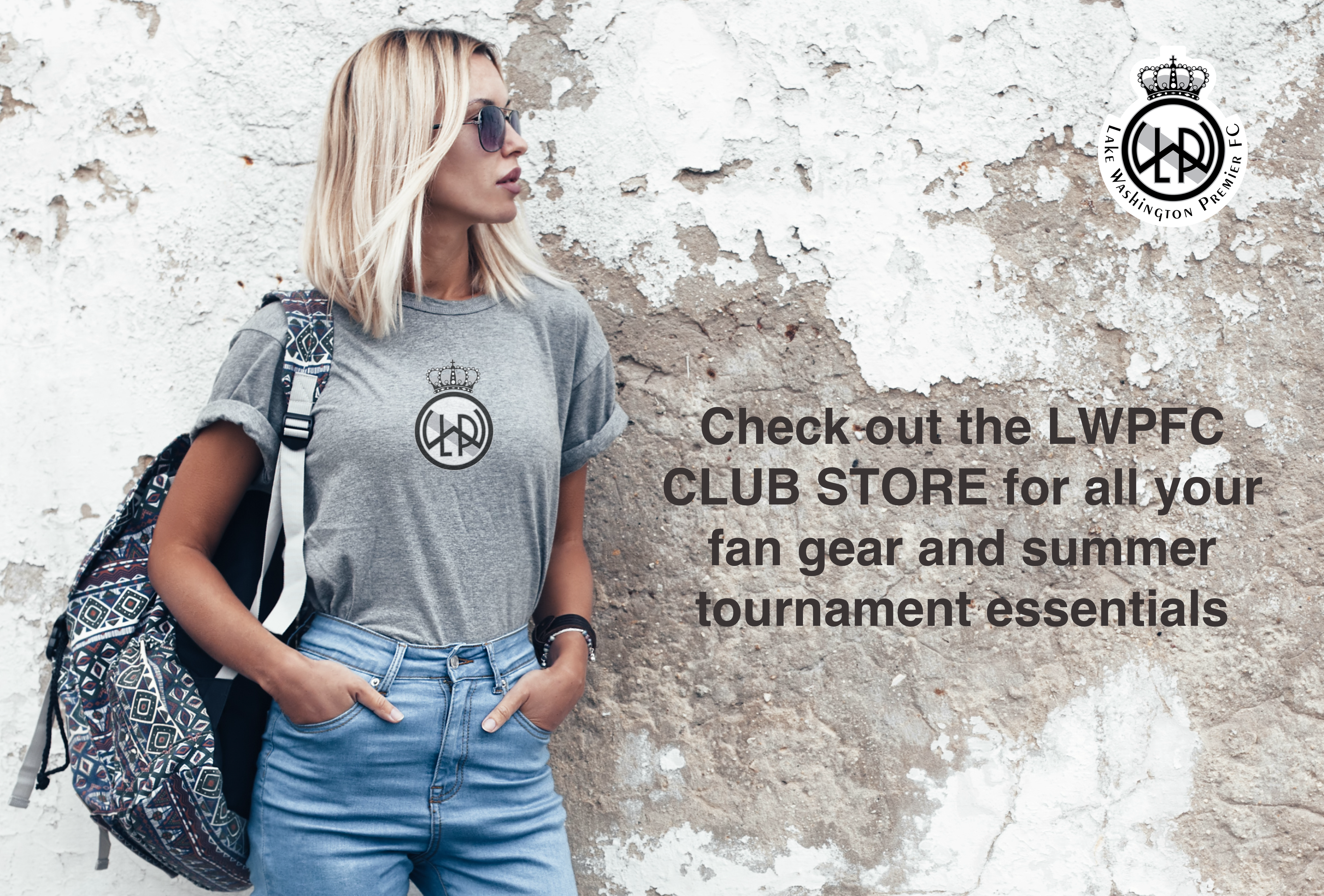 Female soccer fan wearing a stylish black and white LWPFC Club crest print on a gray t-shirt leaning against a wall with fading plasterwork.