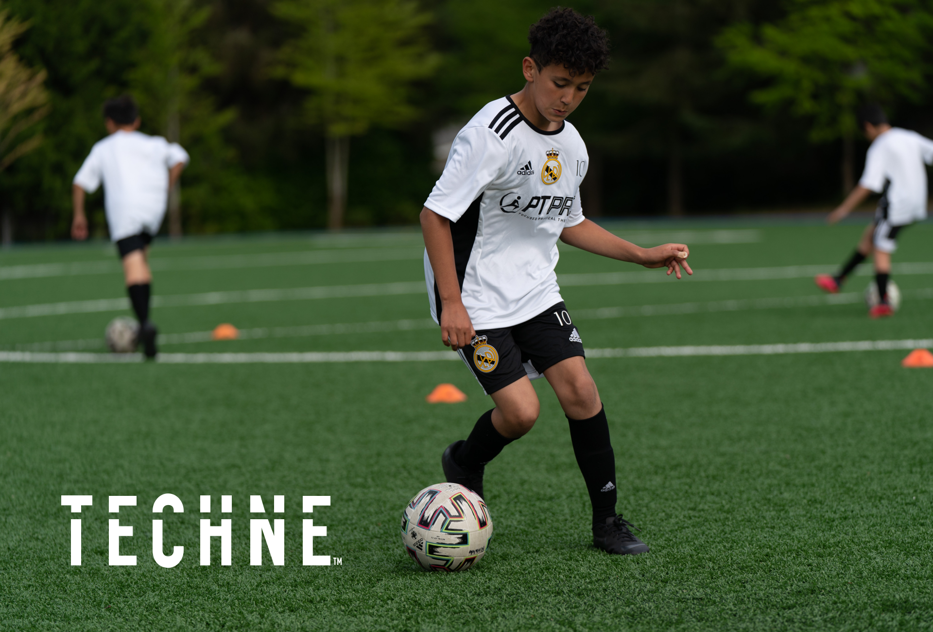 Young soccer player dribbling a ball through cones on a turf field